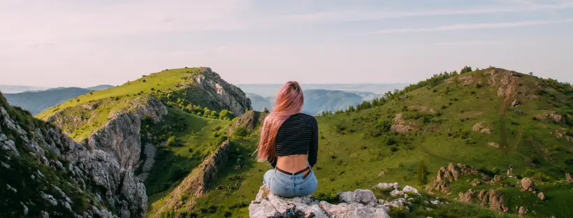 Person sitting alone on a mountain, facing vast landscape, symbolizing how overwhelming meditation can feel when the nervous system is dysregulated