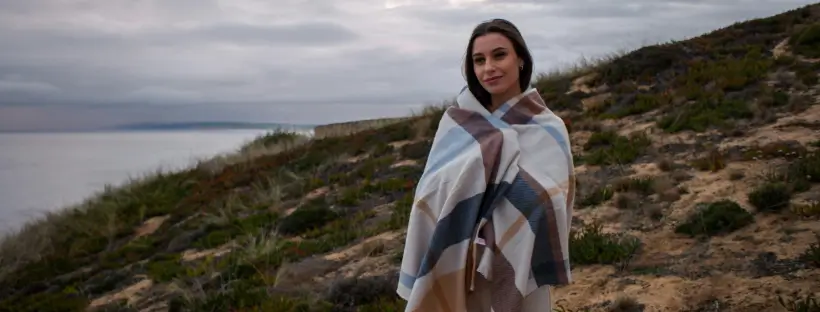 Woman wrapped in a soft blanket standing outdoors, symbolizing the safety and self-reg