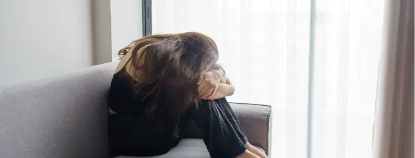 Person sitting curled on a couch in emotional distress, representing how meditation can feel overwhelming when the nervous system is dysregulated
