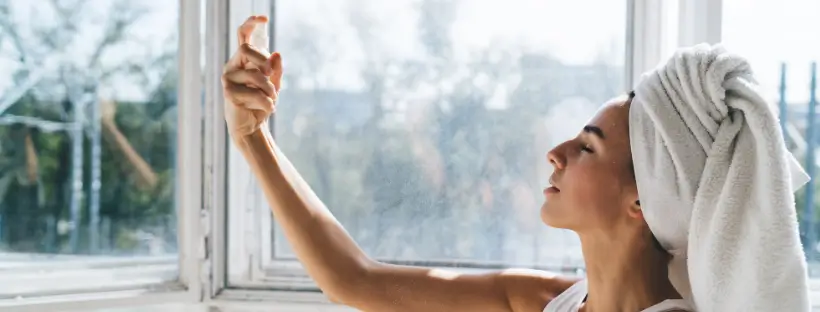 Woman calmly misting her face with a clean hydration spray—part of a nervous system–safe beauty routine.