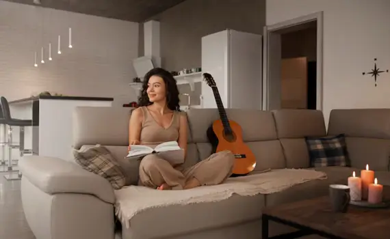 Woman journaling and smiling softly in a cozy home setting.
