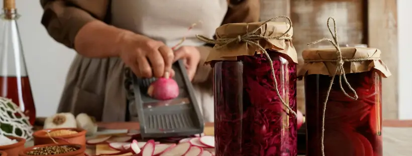 Person slicing radishes next to jars of homemade fermented vegetables to support gut health