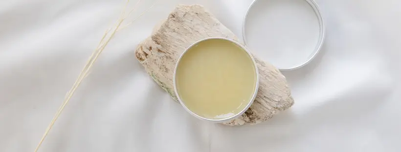 Solid waterless skincare balm in reusable tin on natural fabric and wood, representing concentrated clean beauty with no fillers or preservatives.