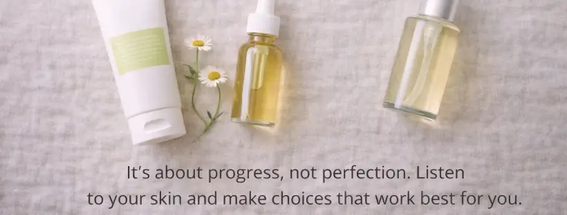 Flat lay of clean skincare bottles with chamomile flowers and quote about listening to your skin, symbolizing progress over perfection in clean beauty routines.